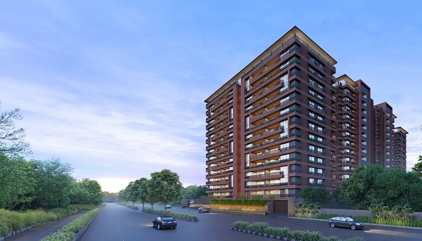 Rivanta-2 residential tower with a warm brick facade beside a tree-lined road at dusk